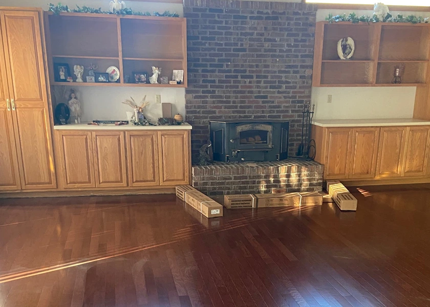 Hardwood flooring with a brick fireplace and built-in cabinetry